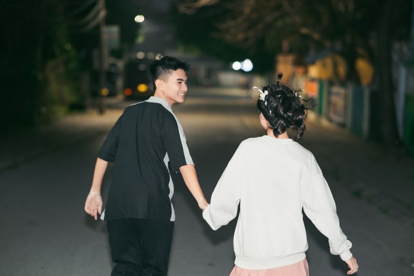 A couple holding hands on a quiet night walk, smiling at each other